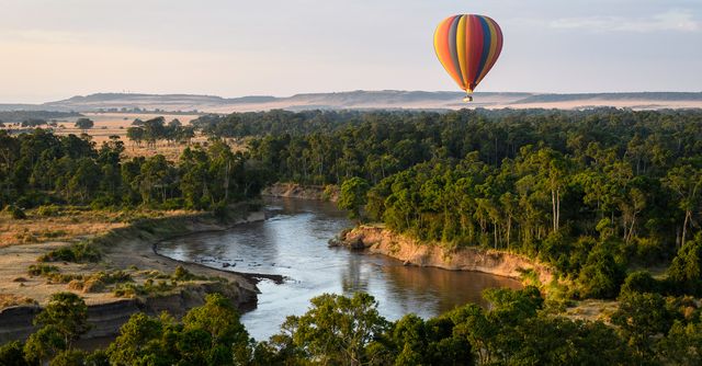 Hot air balloon floating over African savanna at sunrise