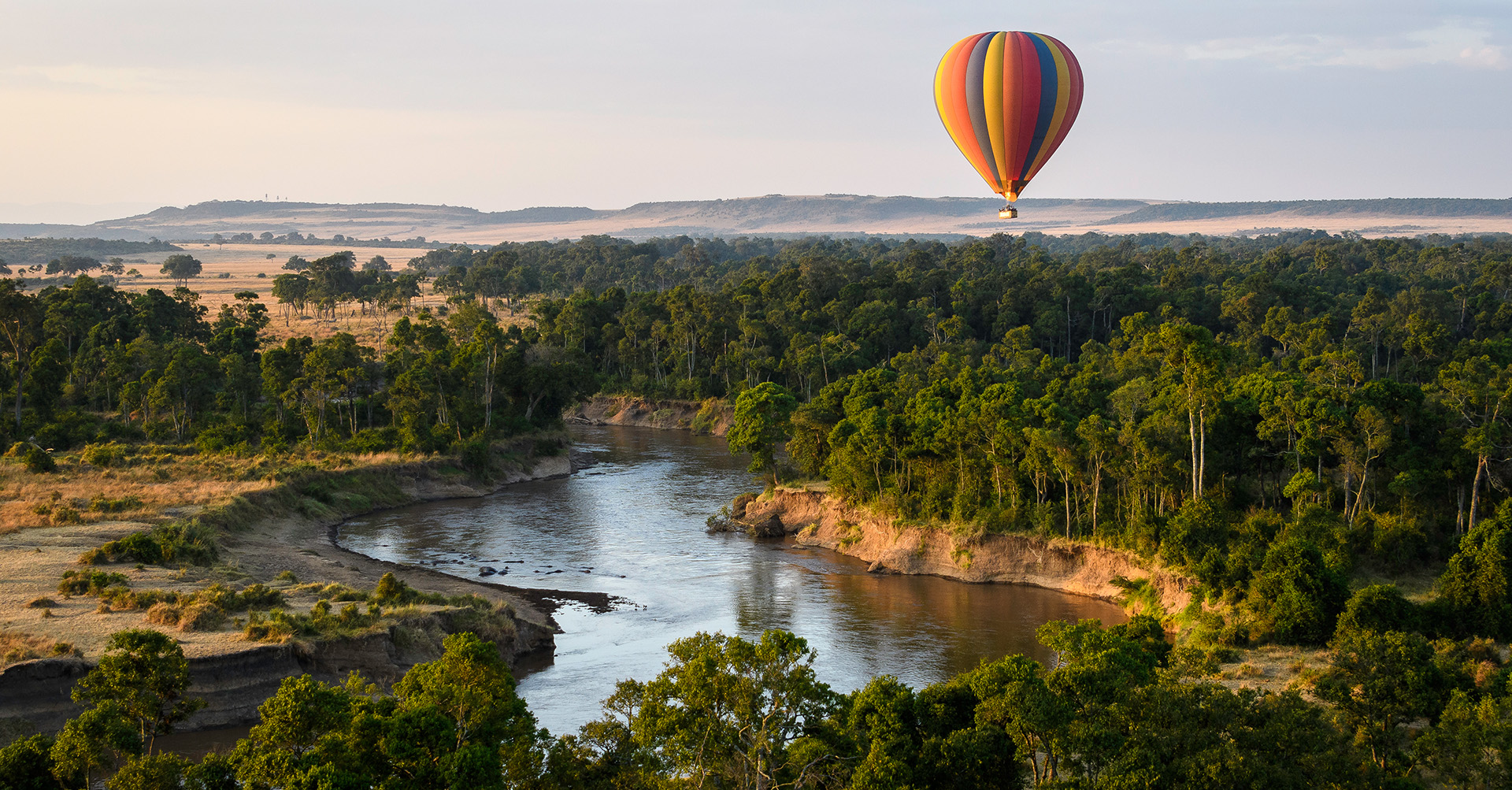 Hot air balloon drifting over the Mara at sunrise